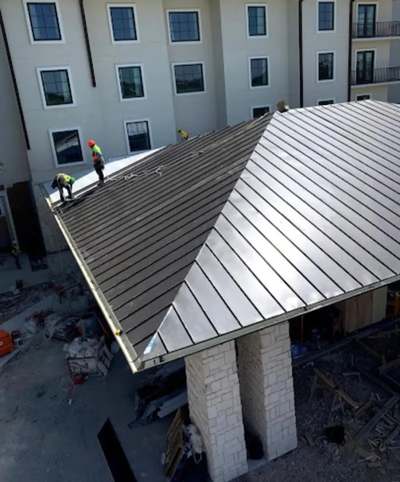 Crew installing standing seam metal roof panels on a commercial project in Wilmer